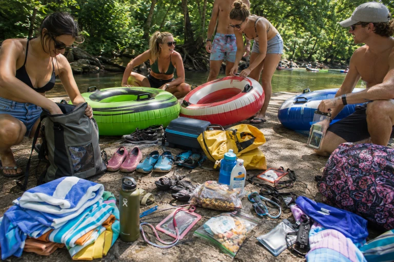 River tubing essentials arranged beside inflatable tubes near a wooded creek